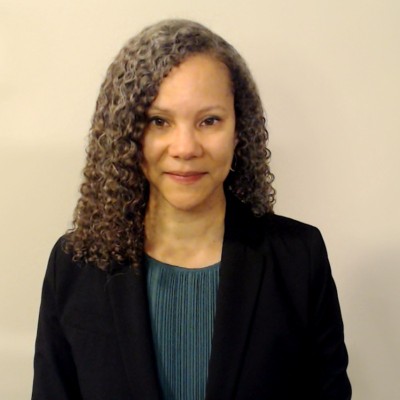 woman with curly brown hair smiling with close lips